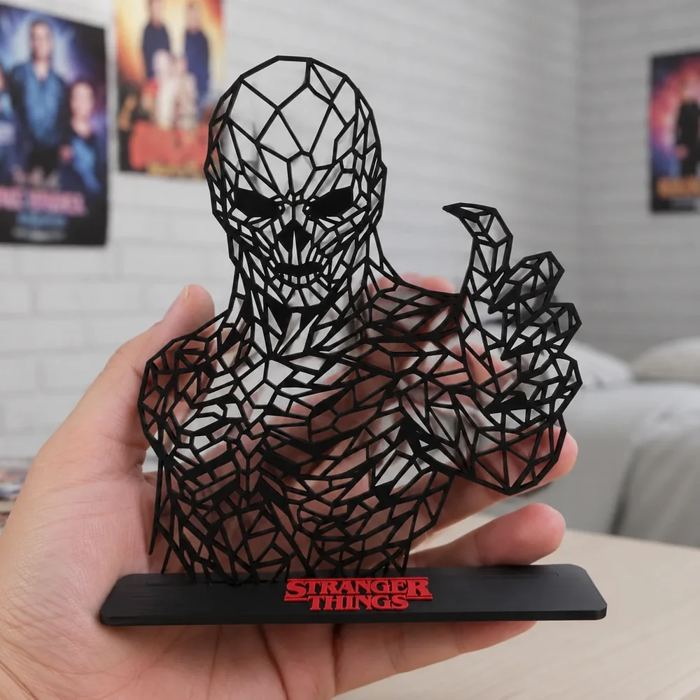 Escultura vazada em estilo low poly, na cor preta, sobre uma base, segurada na mão